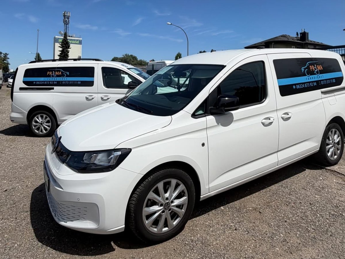 Zwei weiße VW Caddy von Prima Fahrdienst nebeneinander im Sonnenschein, einsatzbereit